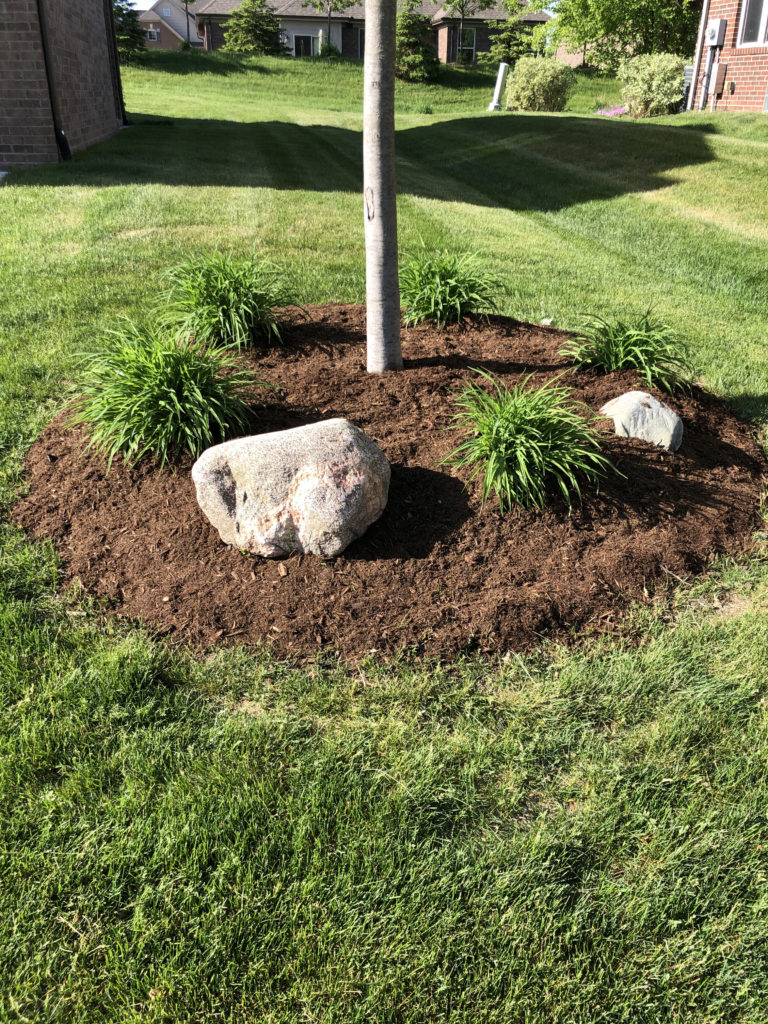 Image of newly-installed mulch and stones in residential landscape by J & J Landscaping, LLC