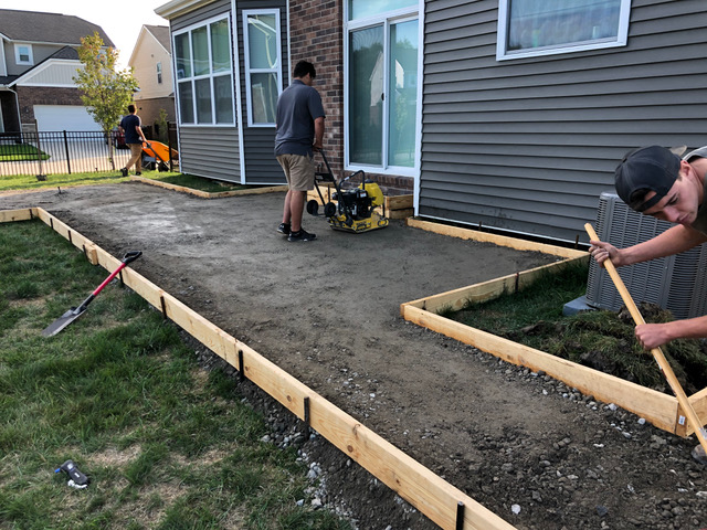 Landscapers preparing for a new concrete patio during a full backyard revamp landscaping project including new landscaping, a cement patio, and sod in Clinton Township, MI