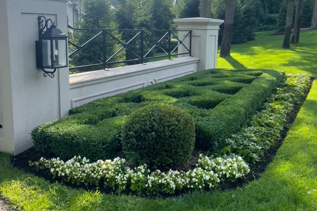 Perfectly trimmed shrubs and bushes surrounded by flowers on a Metro Detroit property featuring a landscape designed and built by J & J Landscaping