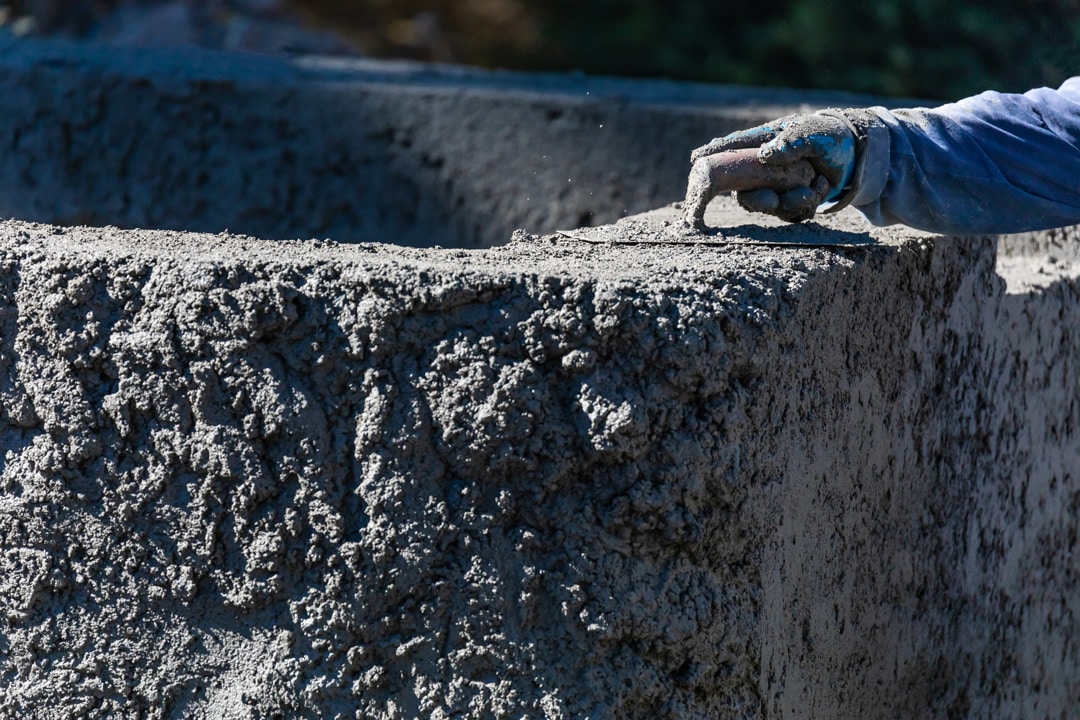 A worker smooths fresh concrete as part of a landscaping and hardscaping project in Metro Detroit