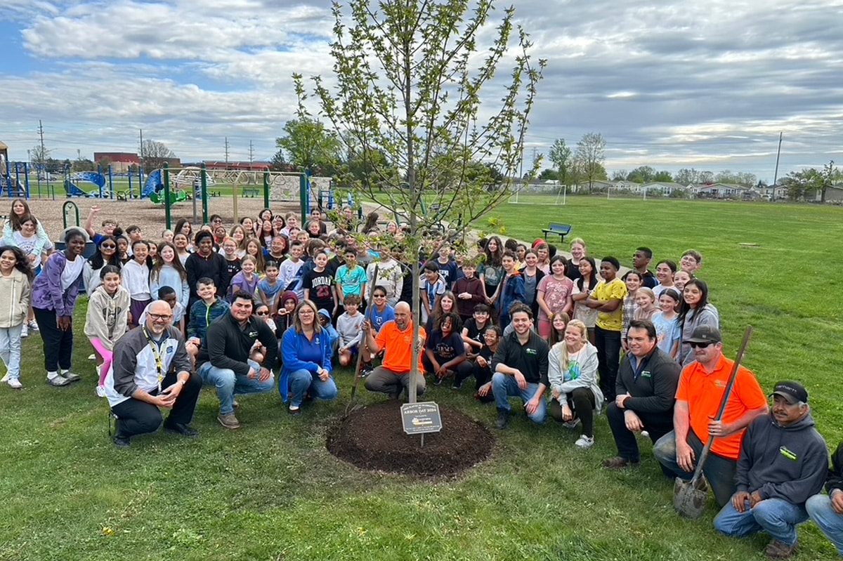 Students from Ojibwa Elementary pose with the J & J Landscaping team in front of their new Autumn Blaze Maple tree donated by J & J