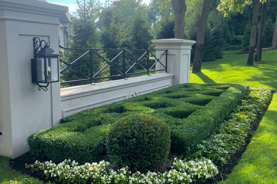 Perfectly trimmed shrubs and bushes surrounded by flowers on a Metro Detroit property featuring a landscape designed and built by J & J Landscaping