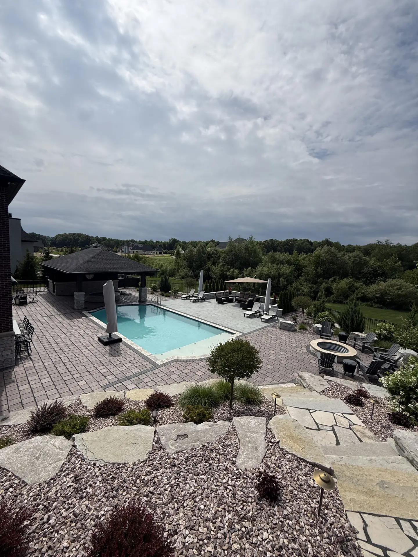 A residential backyard landscape and patio surrounding a pool installed by J & J Landscaping in Washington Township, Michigan.